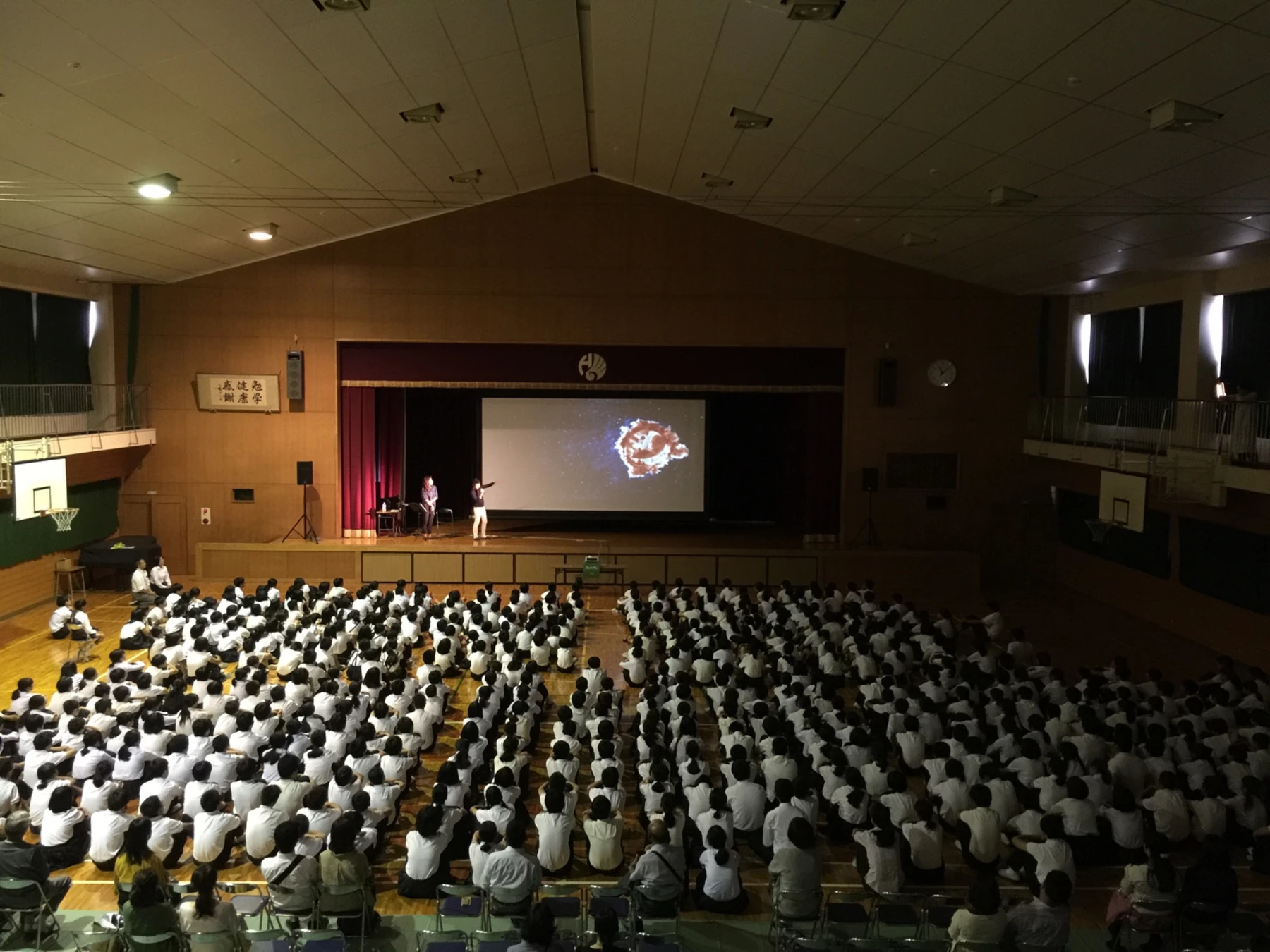 体育館に設置したスクリーンで、LIFEの映像とトークを鑑賞する生徒たち