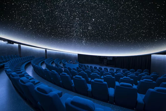 星空が広がるプラネタリウムのドームと青い客席