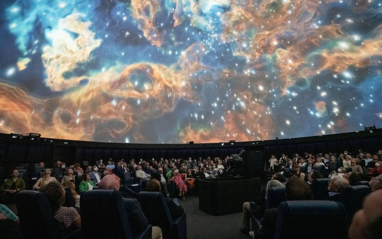 星雲の映像が広がるプラネタリウムのドームと観客